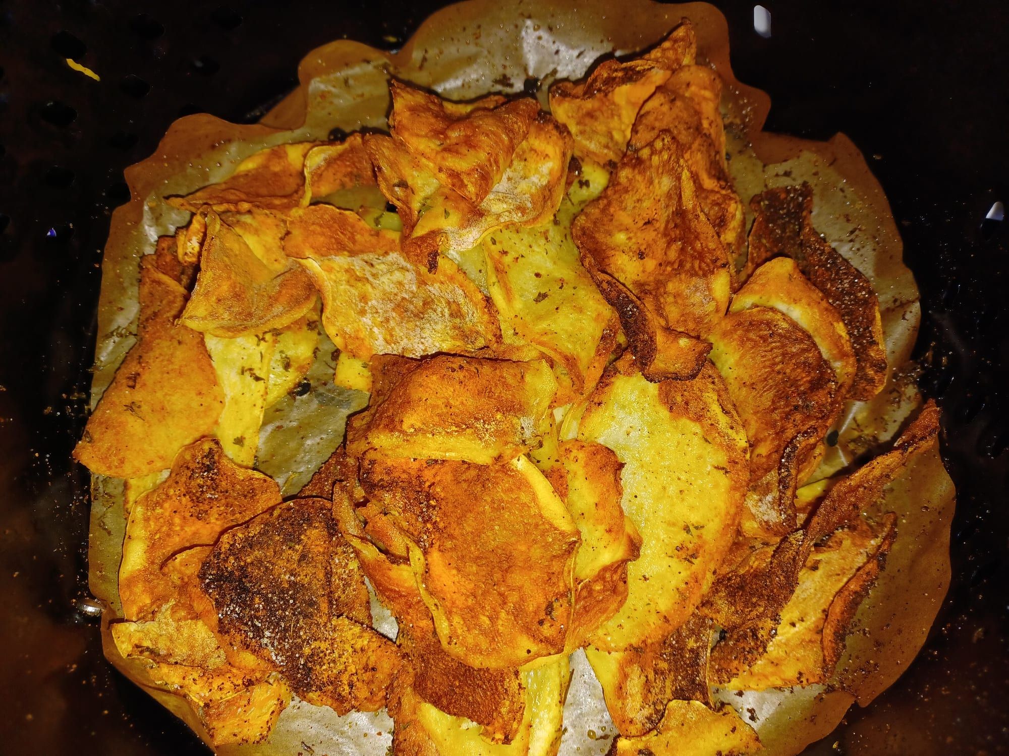 Crisp air-fried potato chips on parchment in an air fryer basket