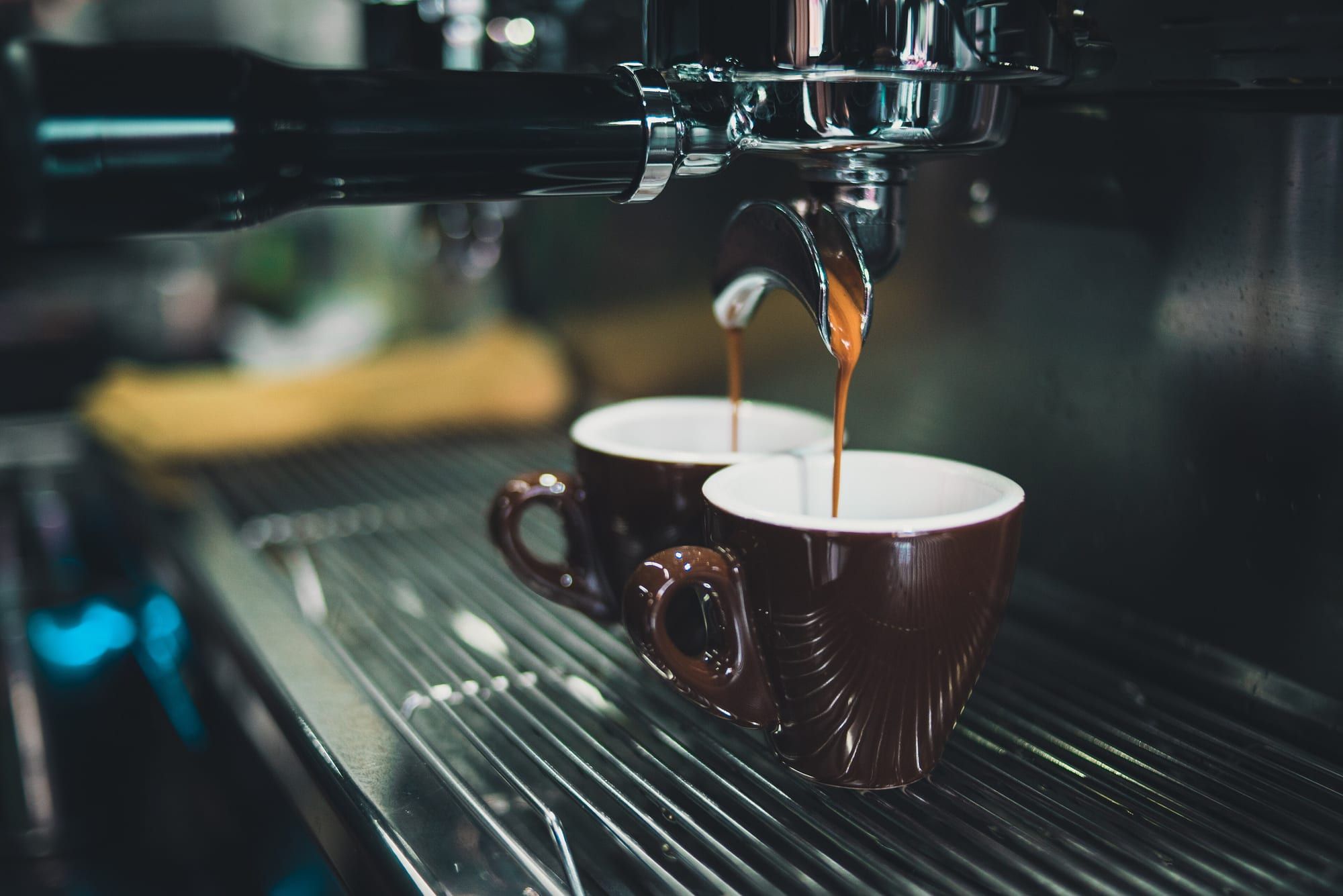 Close-up of an espresso machine with two brown cups under the group head