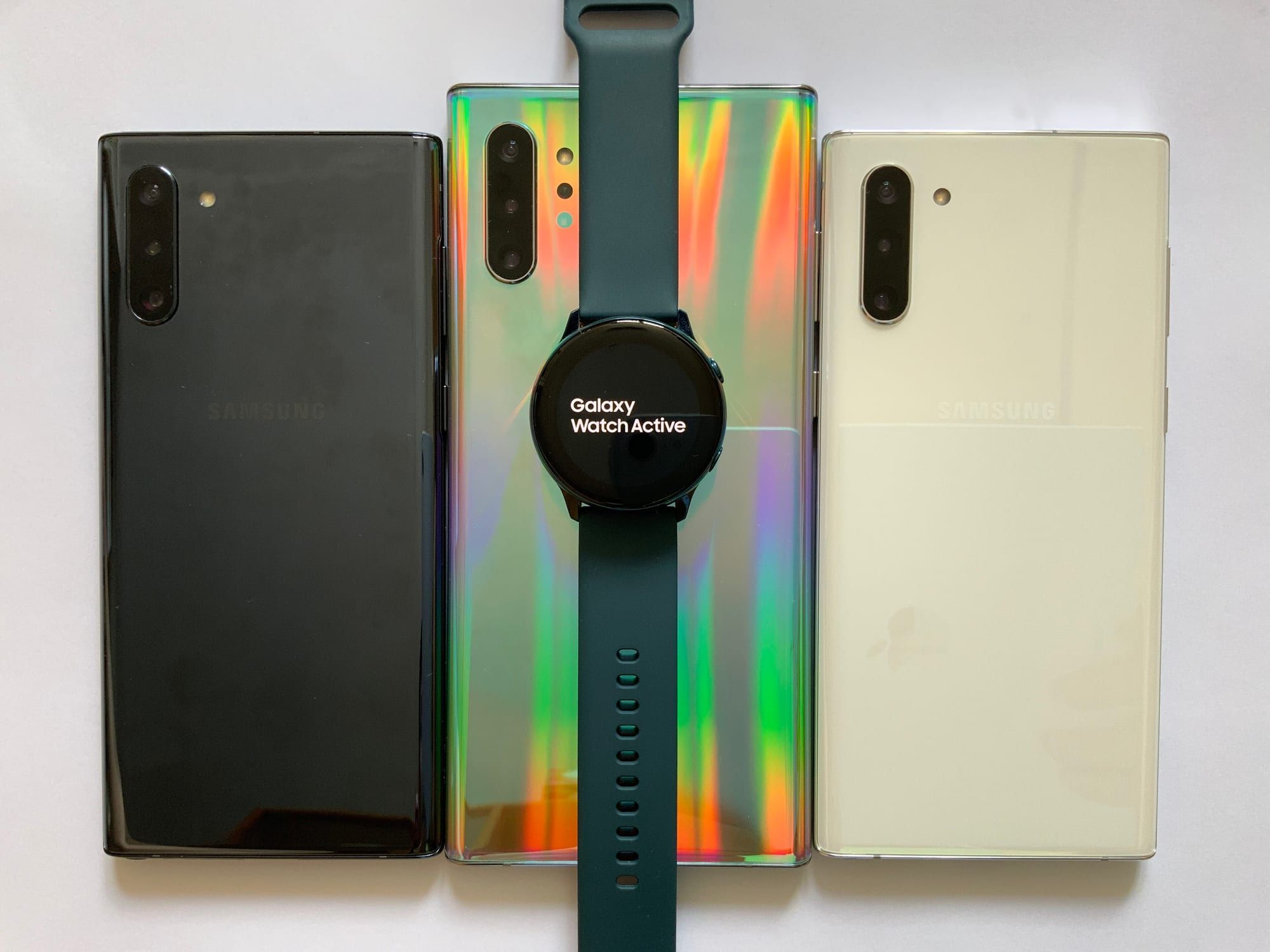 A Samsung Galaxy Watch Active smartwatch lying across three older Samsung Galaxy Note phones
